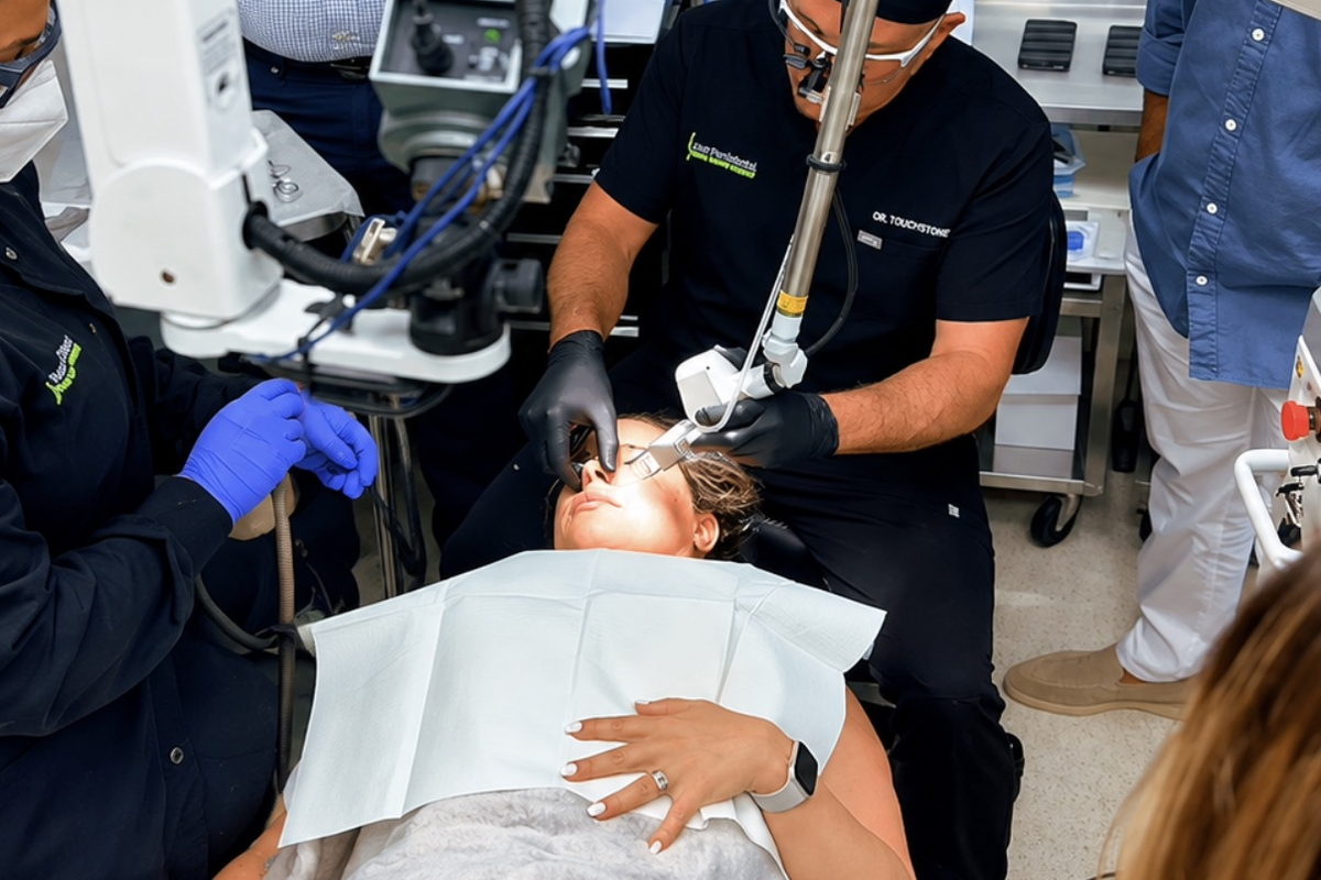 Faculty performing a live DEKA laser facial treatment while course participants observe